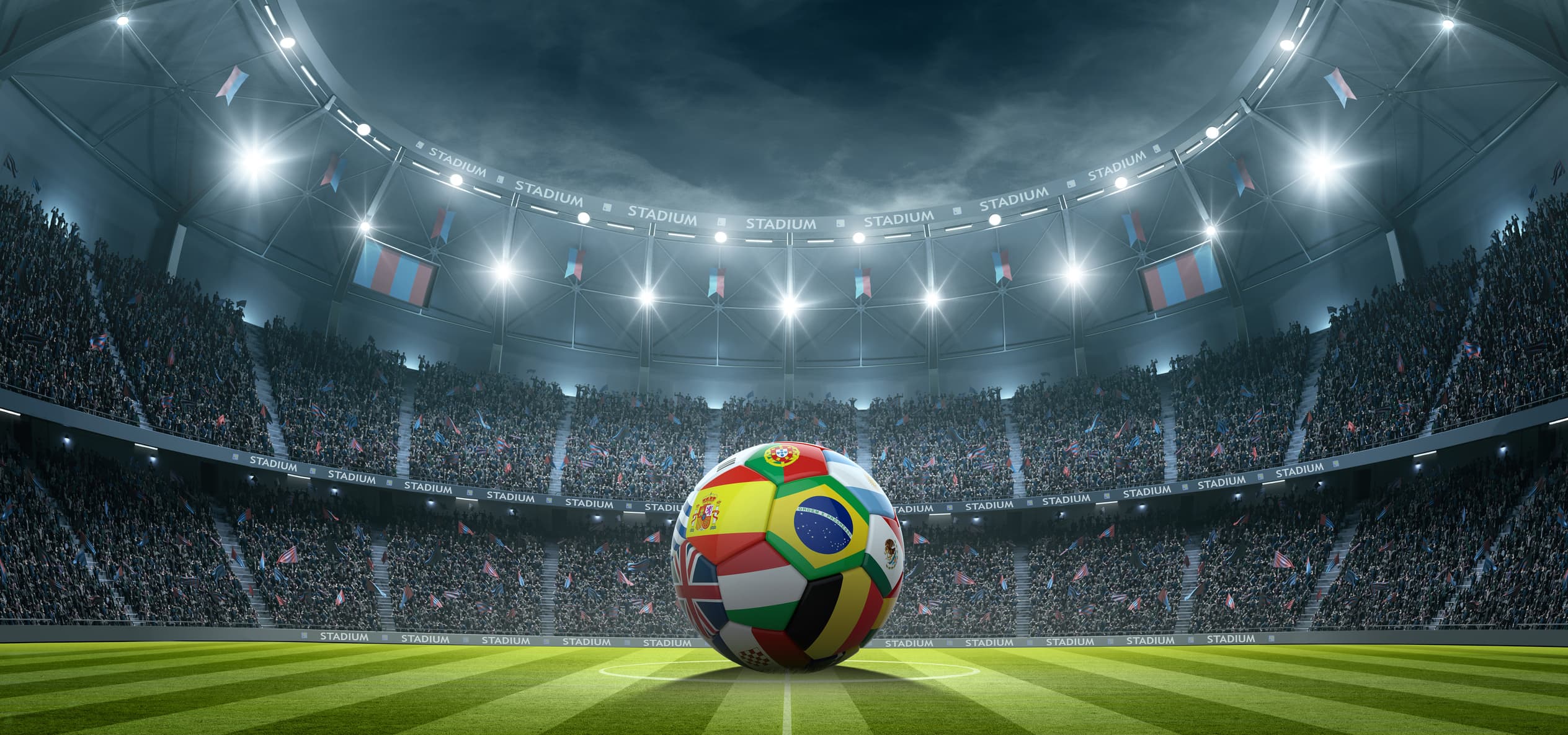 A soccer ball on the pitch under stadium lights
